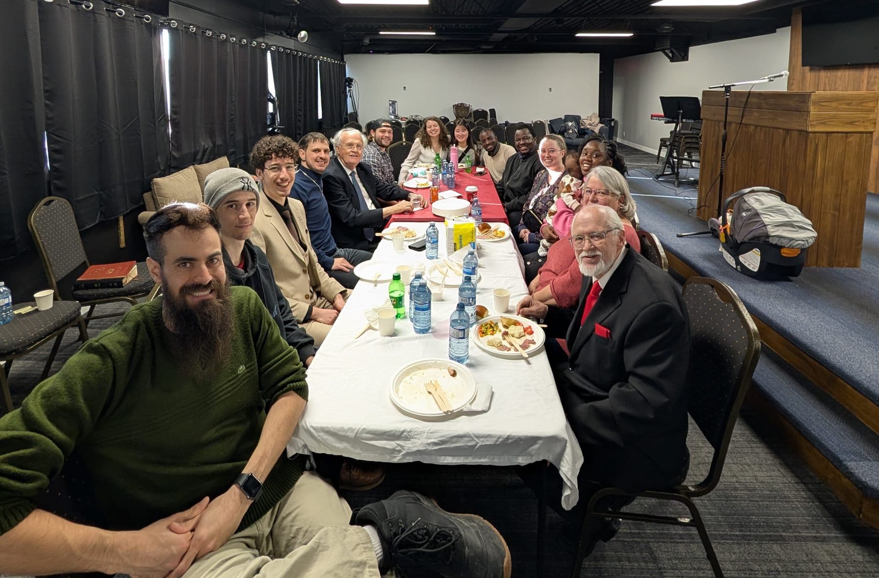 Church members around tables sharing a meal after the meeting